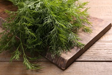 Board with sprigs of fresh dill on wooden table, closeup