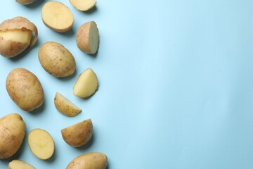 Fresh raw potatoes on light blue background, flat lay. Space for text