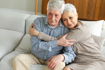 Senior adult mature couple hugging at home. Mid age old husband and wife embracing with tenderness...