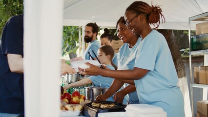 Generous volunteers wearing blue t-shirts, give free meals and humanitarian relief to those in...