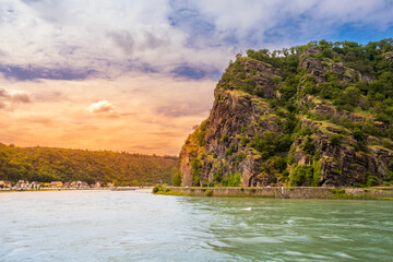 Lorelei rock at sunset. Bank of Rhine river near Sankt Goarshausen town in Rhineland-Palatinate, Germany. Landscape of River Rhein and famous Loreley mountain in Rhine Gorge