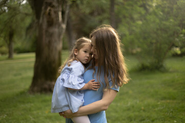 Mother and daughter share a comforting embrace in a peaceful park.