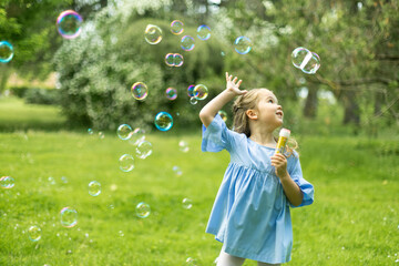 Young girl playing with bubbles in vibrant park setting.