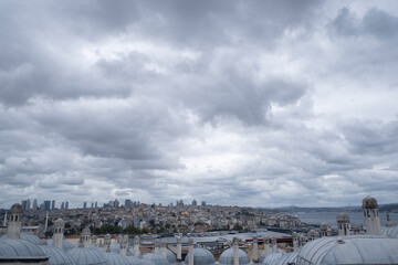 panoramic view of the city of Istanbul from the viewpoint of the Suleiman Mosque, with its typical roofs in the foreground, on a cloudy day with stormy atmosphere