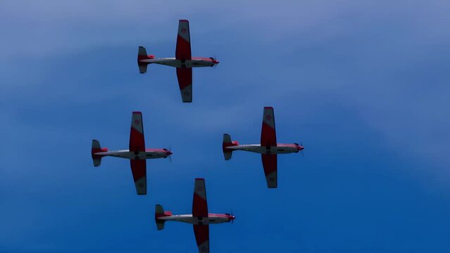 Quartet of propeller-driven trainer aircraft in tight formation, silhouetted against the blue hues of the evening sky, showcasing precision and teamwork in aerial maneuvers at dusk