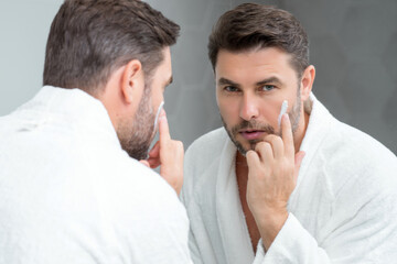 Beauty man applying face cream. Skincare cream, skin anti-aging wrinkle effect. Man applying...