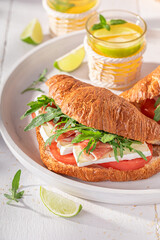 Delicious and golden french croissant with prosciutto, camembert and arugula.