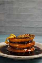 Vertical image of sopaipillas pasadas, topped with an orange peel. on a light blue wooden table on a rustic white wall background. Typical Chilean food