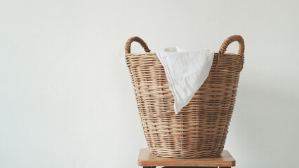 Wicker laundry basket with clean clothes with copy space on a wood table against the white background. Space for text or product.