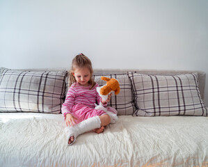 cute little girl with plaster cast , resting at home playing with toy