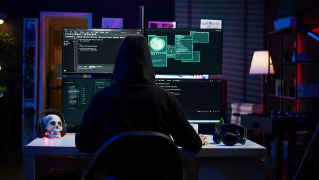Lone wolf hacker in secret hideout trying to hide online activity after stealing data. Cybercriminal attacking victims PCs using computer virus, trying to avoid being detected, camera B