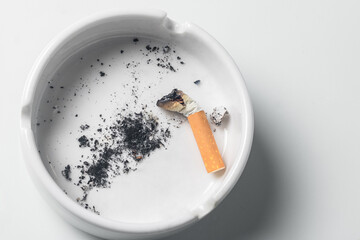 Porcelain cigarette ashtray with white background, tobacco ash.