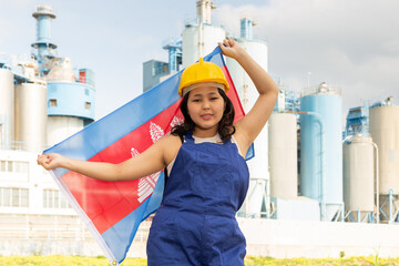 Happy young woman with helmet holding big flag of Cambodia against background of factory