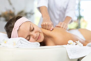 Image showcases close-up of female masseur skillfully working on shoulder area and back of female...