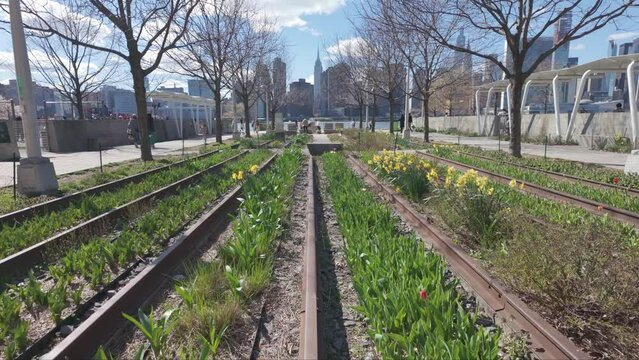Long Island City railroad tracks leading to New York City empire state building trees grass flowers blue sky