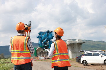 Construction engineer using a level survey for the construction foundation of the electric train...