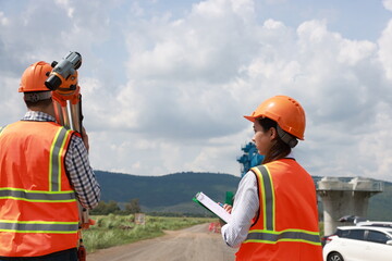 Senior construction male  engineer training a young new female  engineer and using a digital tablet with a hold walkie-talkie in his hand at the infrastructure of Sky bridge