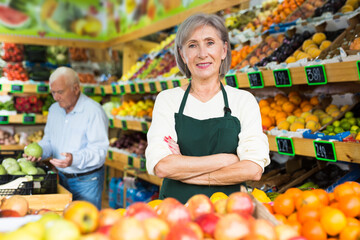 Female supermarket worker stacking fruits on shelf in salesroom