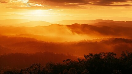 Obraz premium A mountainous landscape glowing in shades of orange and gold as the sun dips below the horizon.