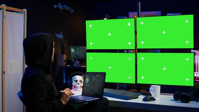 Man writing code on laptop in front of isolated screen PC monitors, trying to get past security systems. Hacker using chroma key computer and notebook to make scripts that can hack devices, camera B