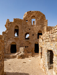 Sun-drencher ancient ruins of traditional fortified structures of Ksar Beni Barka with remains of mud brick rooms used for dwelling and granaries, Tataouine, Tunisia..