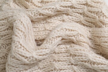Beige knitted scarf as background, closeup view
