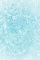 Blue water with ripples on the surface. Defocus blurred transparent blue colored clear calm water surface texture with splashes and bubbles. Water waves with shining pattern texture background.