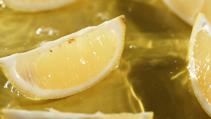 Top down view of lemon slices splashing in water on yellow background. Close up of fresh lemon...