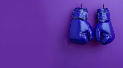 A pair of blue boxing gloves hanging on a purple wall. The gloves are made of smooth leather and have silver accents.