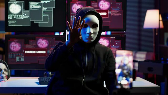 Hacker concealing identity filming ransom video in hidden underground base, threatening to release stolen data publicly if payout demands are not met, using phone to record blackmail footage, camera A