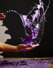 Throwing violet paint from hand to the wall on black background, AI generative