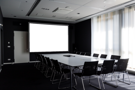 Big white screen in the black meeting room. Empty room for a conference, presentation or forum
