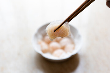 Dim sum for Chinese breakfast tea includes steamed shrimp dumplings served on a round plate with oiled paper.