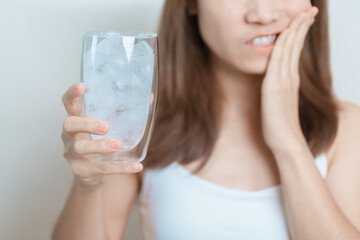 Teeth Sensitive to Cold concept. woman hold Ice Water glass and having toothache and pain after...