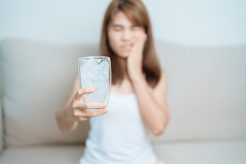 Teeth Sensitive to Cold concept. woman hold Ice Water glass and having toothache and pain after eat. Tooth Decay or Gum Disease, Grinding Teeth and Stress, Exposed Nerve Roots, Crack and Receding Gums