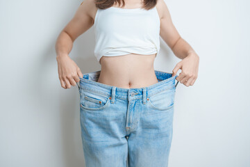 young slim female wearing big or oversize jeans, woman show healthy shape after weight loss....