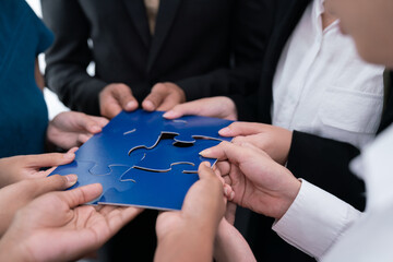 Diverse corporate officer workers collaborate in office, connecting puzzle pieces to represent...