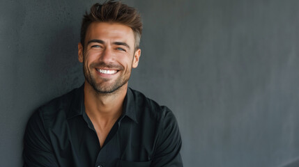 Fototapeta premium Smiling young man in casual black shirt against dark background