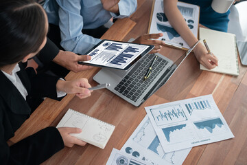 Multiracial analyst team use BI Fintech software to analyze financial data on meeting table. Financial dashboard data display on laptop screen with analyzed chart for marketing indication. Concord