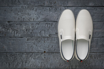White Slip-On Shoes on Dark Wooden Surface - Casual Footwear and Rustic Background