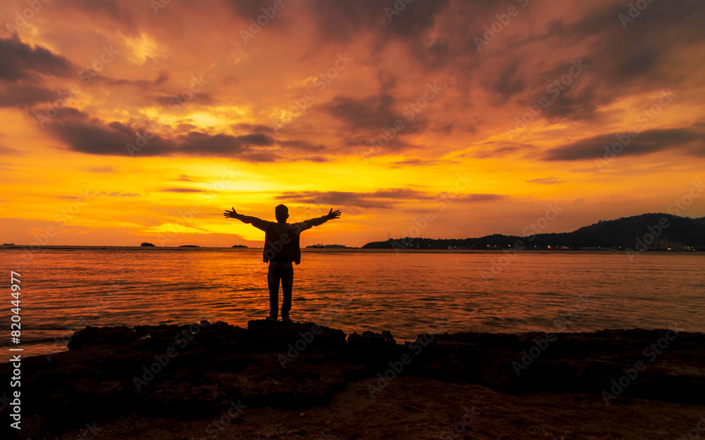 Wall mural silhouette of a man standing at shoreline