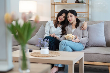 pride month Happy women lesbians lgbt couple spending time together at home in the evening, relaxing, watching movie together in the living room. LGBTQ couple concept