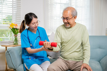 Young nurse physiotherapist helping old man in lifting dumbell at home, Asia nurse support elderly...