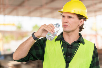 Caucasian engineer man drinking water at the precast factory site, Worker man drinking water at...