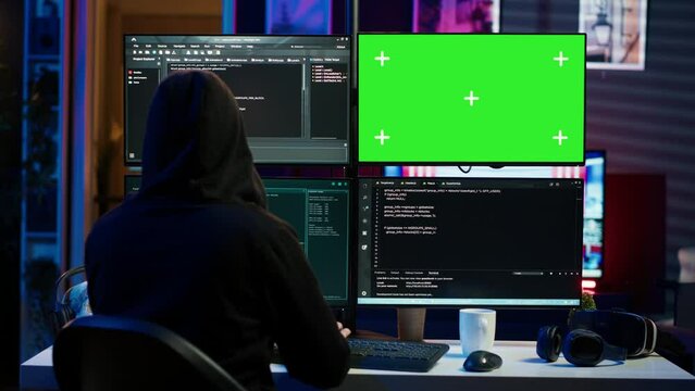 Dangerous man hacking using green screen PC, stealing credit card numbers and infiltrating banking systems. Hacker running code in apartment on mockup computer display, camera A