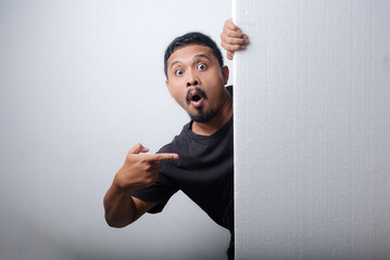 man peeking behind blank sign
