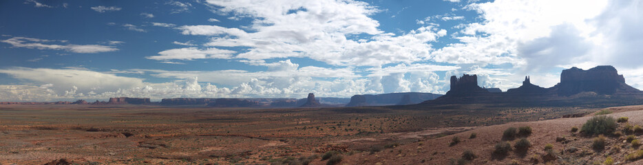 Monument valley wide panoramic view on sunny day, distant buttes and mesa rock formations, contrast contour