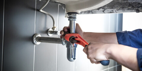 Plumber uses wrench to repair water pipe under sink There is maintenance to fix the water leak in...