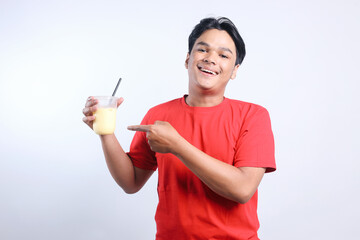 Cheerful Young Asian Man Pointing Juice Drinks Isolated On White Background. 