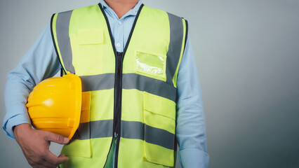 Civil engineer architect standing holding a safety helmet on grey background, Construction site plans to build high-rise buildings, Engineer building concept, Background for construction.